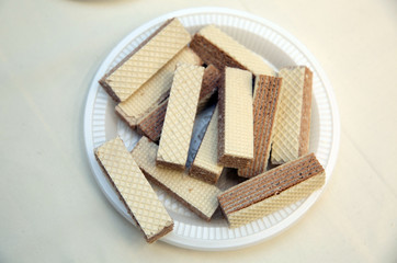 Various confectionery on plate, wafer witch chocolate layers and cookies on white background . waffles in a white plastic plate.