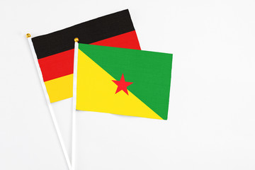 French Guiana and Germany stick flags on white background. High quality fabric, miniature national flag. Peaceful global concept.White floor for copy space.