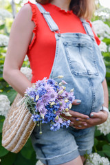 pregnant girl waiting for the baby holds her stomach with a basket of flowers