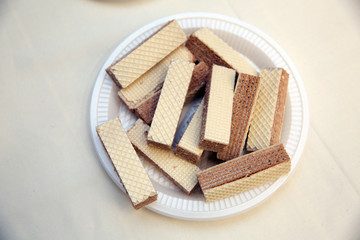 Various confectionery on plate, wafer witch chocolate layers and cookies on white background . waffles in a white plastic plate.