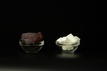 Replacing traditional sugar with figs, healthy nutrition. Transparent glass bowls, figs and sugar on a black background.
