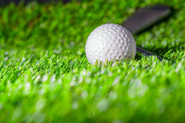 Golf ball with golf club on green grass