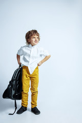 Pretty young boy in casual clothes on white studio background. Fashionable posing. Caucasian male preschooler with bright facial emotions. Childhood, having fun. Expressive emotions, screaming.