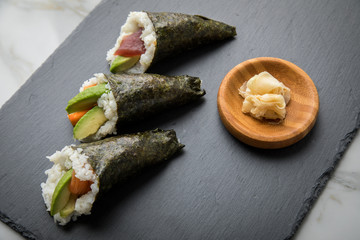 Lachs Fisch, Tunfisch und Surimi Avocado Temaki Sushi, eingelegter Ingwer und Wasabi auf Schiefer...