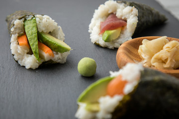 Lachs Fisch, Tunfisch und Surimi Avocado Temaki Sushi, eingelegter Ingwer und Wasabi auf Schiefer Platte und Marmor Hintergrund