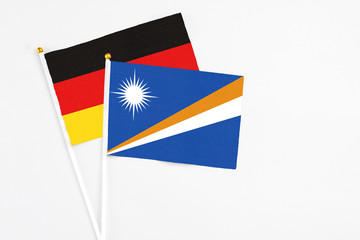 Marshall Islands and Germany stick flags on white background. High quality fabric, miniature national flag. Peaceful global concept.White floor for copy space.