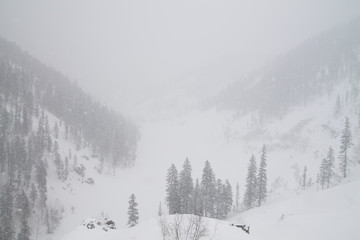 Winter landscape with heavy snowfall in mountains and gray sky