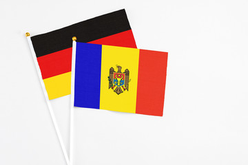 Moldova and Germany stick flags on white background. High quality fabric, miniature national flag. Peaceful global concept.White floor for copy space.
