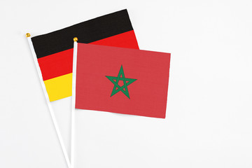 Morocco and Germany stick flags on white background. High quality fabric, miniature national flag. Peaceful global concept.White floor for copy space.
