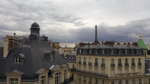 Revealing shot of Parisian rooftops with Eiffel tower in background  at sunset