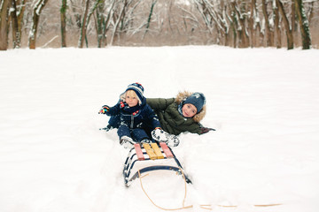 Fototapeta na wymiar Happy brothers lying on snow outdoors. Kids having fun together in winter park. Happy and healthy childhood