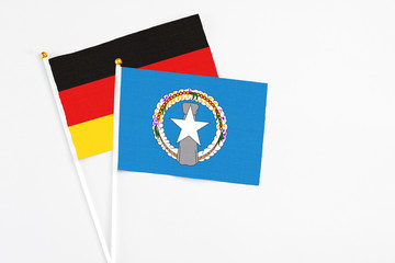 Northern Mariana Islands and Germany stick flags on white background. High quality fabric, miniature national flag. Peaceful global concept.White floor for copy space.