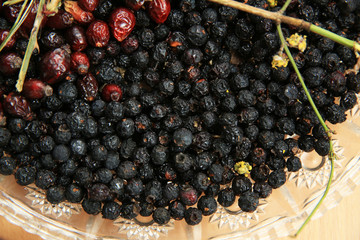 Hawthorn on wooden rustic table background. Rose hips haw fruit of the dog rose. Black chokeberry berries jam .