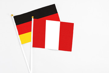 Peru and Germany stick flags on white background. High quality fabric, miniature national flag. Peaceful global concept.White floor for copy space.