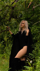 sexy blonde woman in black cloak nature