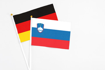 Slovenia and Germany stick flags on white background. High quality fabric, miniature national flag. Peaceful global concept.White floor for copy space.