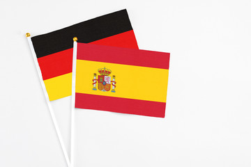Spain and Germany stick flags on white background. High quality fabric, miniature national flag. Peaceful global concept.White floor for copy space.