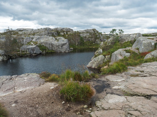 View on small water pond or lake on hike to Preikestolen massive cliff famous Norway viewpoint Moody sky, autumn day. Nature and travel background, vacation and hiking holiday concept.