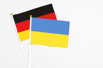 Ukraine and Germany stick flags on white background. High quality fabric, miniature national flag. Peaceful global concept.White floor for copy space.