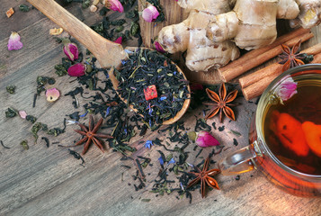 cup of fresh tea and spices. black blended tea, ginger, anise and cinnamon on a wooden table. tea...