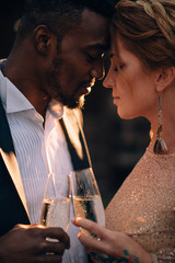 Two lovers with glasses in their hands tenderly leaned against each other, close-up