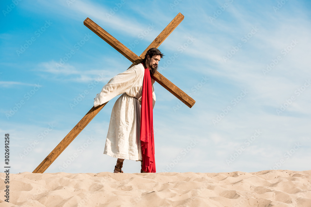 Wall mural jesus in wreath walking with cross in desert