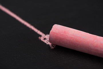 close up view of pink chalk on black surface with drawn line, connection concept