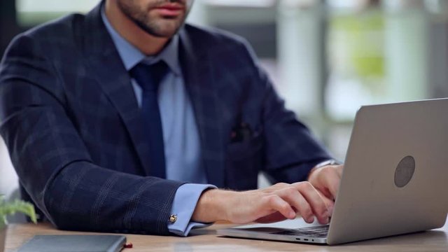 cropped view of businessman typing on laptop 