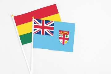 Fototapeta premium Fiji and Ghana stick flags on white background. High quality fabric, miniature national flag. Peaceful global concept.White floor for copy space.