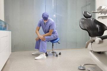 Dentist stretching body. Caucasian man exercising on dental mobile saddle in his office.