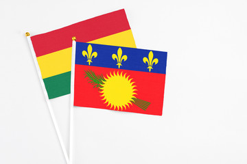 Guadeloupe and Ghana stick flags on white background. High quality fabric, miniature national flag. Peaceful global concept.White floor for copy space.