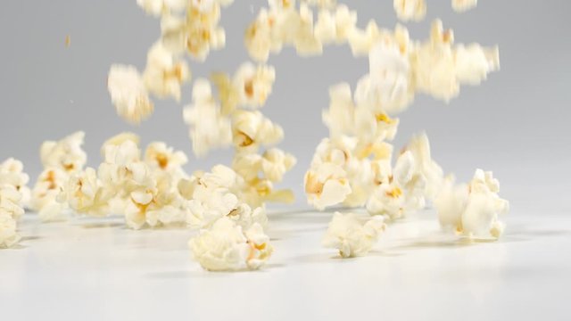 Fresh popcorn falling onto a white surface in slow motion