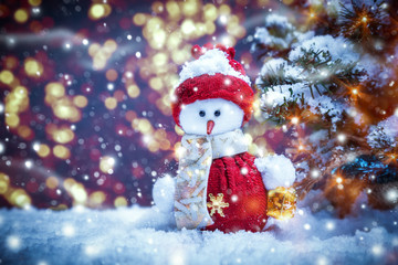 Christmas background with cute snowman toy near the Christmas tree