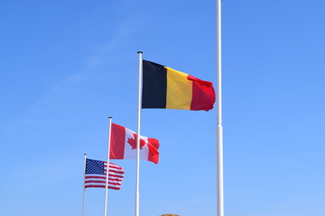 Belgium, Canada and USA flags with a blue sky background. World war two allies symbol. Grateful European country.