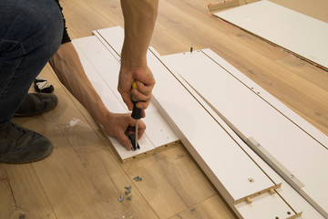 furniture, home and moving concept - close up of male hands assemblying home furniture
