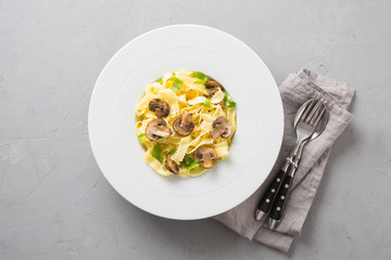 Spaghetti reginelle pasta with mushrooms on grey stone table. Tasty healthy dinner. View from above.
