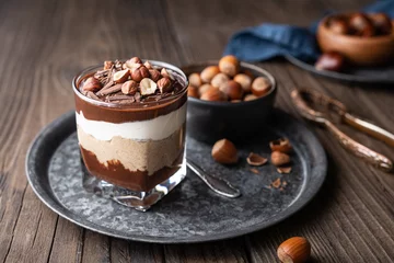 Fotobehang Layered dessert with chocolate mousse, cream cheese and whipped cream mixed with chestnut puree, topped with hazelnuts in a glass jar © Marcus Z-pics