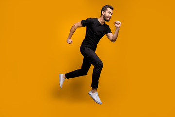 Fototapeta na wymiar Full size photo of handsome millennial guy jumping high rush shopping mall black friday offers season fast wear black t-shirt trousers isolated yellow color background