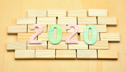 Año 2020 formado por números de madera, sobre muro de ladrillos 