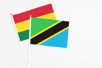 Fototapeta premium Tanzania and Ghana stick flags on white background. High quality fabric, miniature national flag. Peaceful global concept.White floor for copy space.