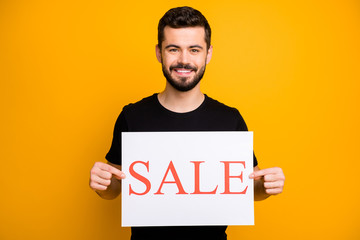 Photo of handsome millennial guy offer low prices shopping showing holding white paper card sale...