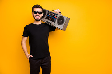 Portrait of cool charming positive guy hold boom box on his shoulder want listen vintage music on journey wear black friday clothes isolated over bright color background