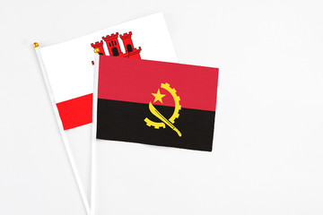 Angola and Gibraltar stick flags on white background. High quality fabric, miniature national flag. Peaceful global concept.White floor for copy space.