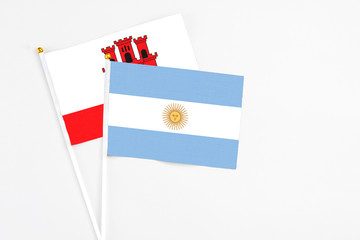 Argentina and Gibraltar stick flags on white background. High quality fabric, miniature national flag. Peaceful global concept.White floor for copy space.