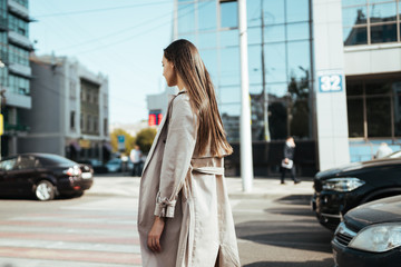 Fototapeta premium A girl in a raincoat sadly wanders through the city among cars and buildings