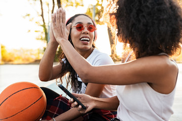 Image of american girls giving high five on basketball playdround