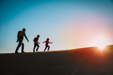 Silhouettes of father with son and daughter hiking at sunset