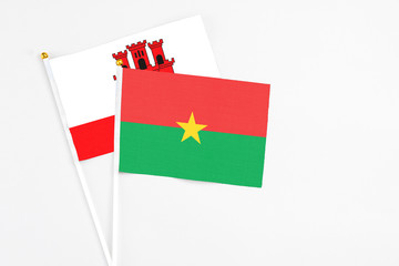 Burkina Faso and Gibraltar stick flags on white background. High quality fabric, miniature national flag. Peaceful global concept.White floor for copy space.