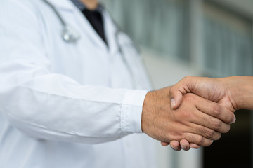 Close up of a doctor shake hands with the patient.