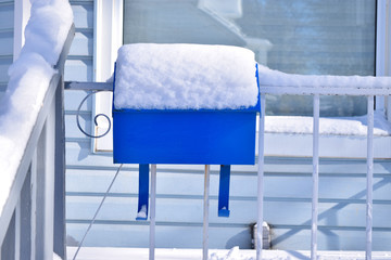 Blue mailbox covered in snow after a storm. Symbol for winter holiday greetings. Christmas and new year's cards. Free space for text.